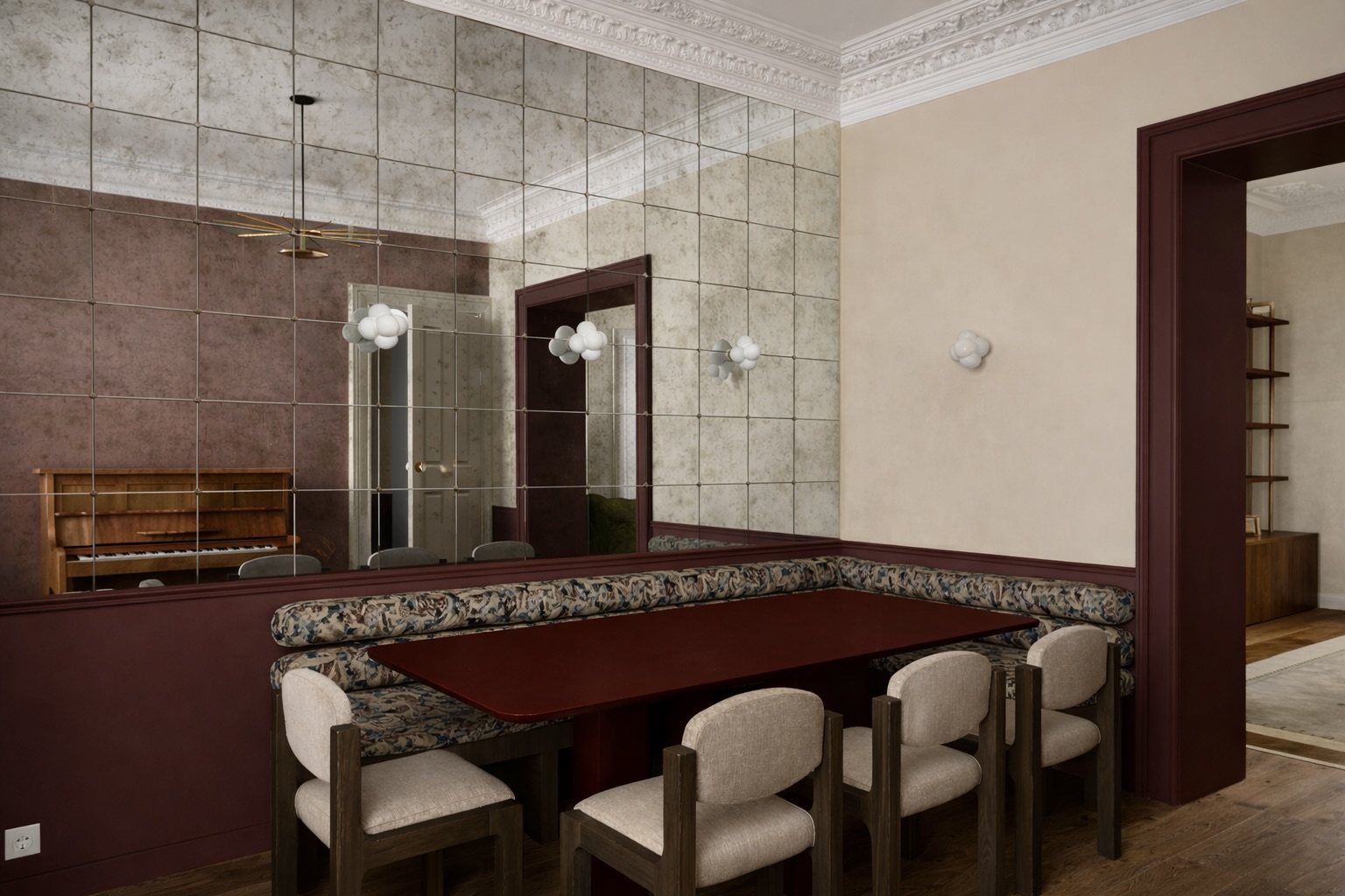 Salle à manger habillée de miroirs anciens patinés, banquette d’angle à motif fleuri, table laquée bordeaux et chaises beige, moulures au plafond